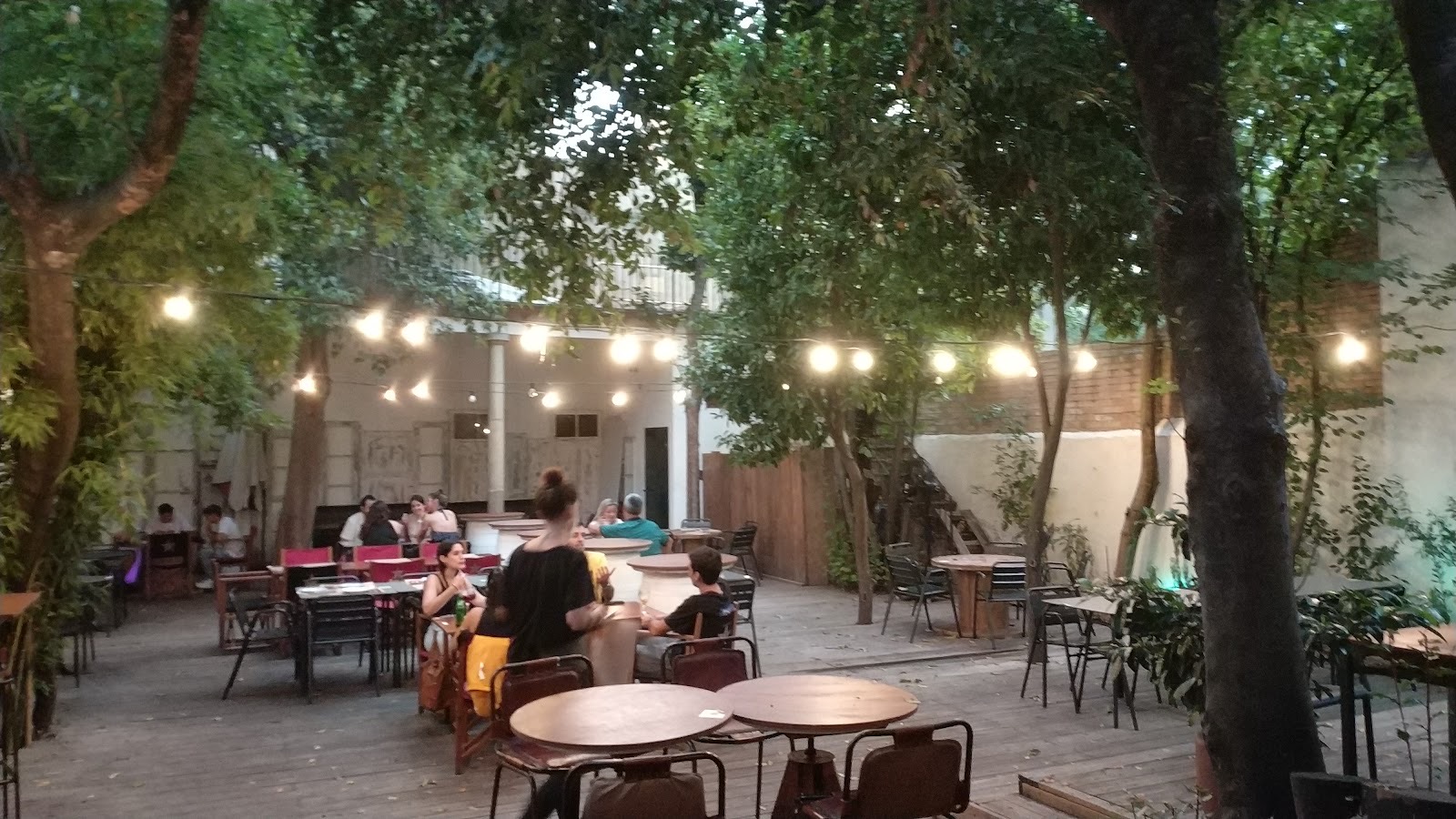 El patio de El Pati al anochecer: mesas bajo los árboles y guirnaldas de luces
